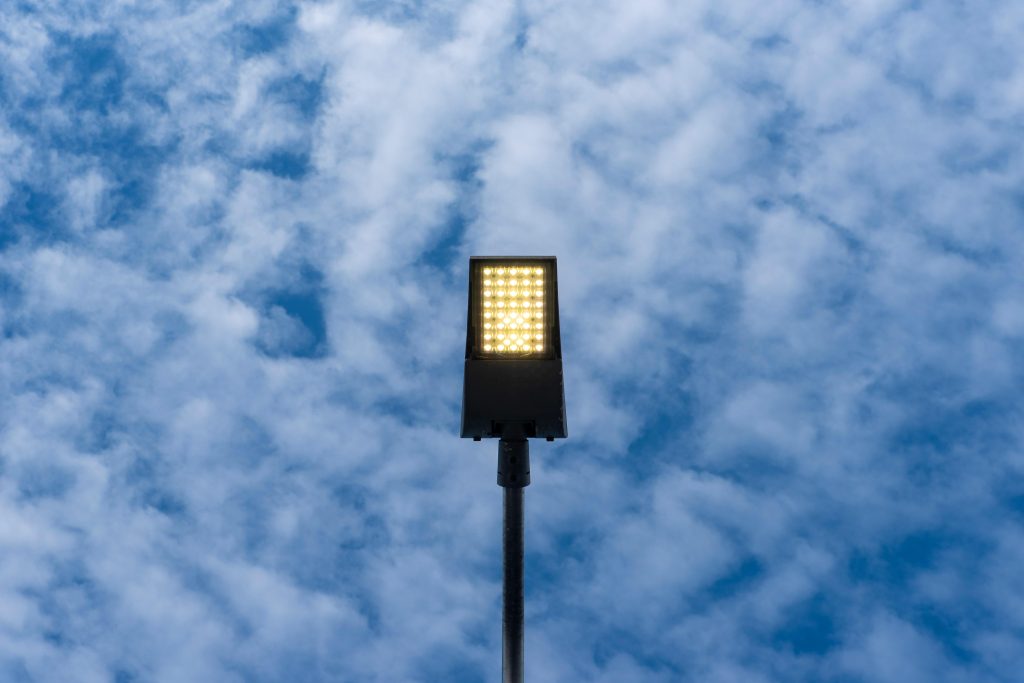 A bright LED street lamp set against a backdrop of blue sky with clouds, creating a contrast.